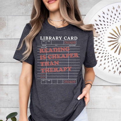 A bella canvas 3001 shirt with the saying "Reading is cheaper than therapy"