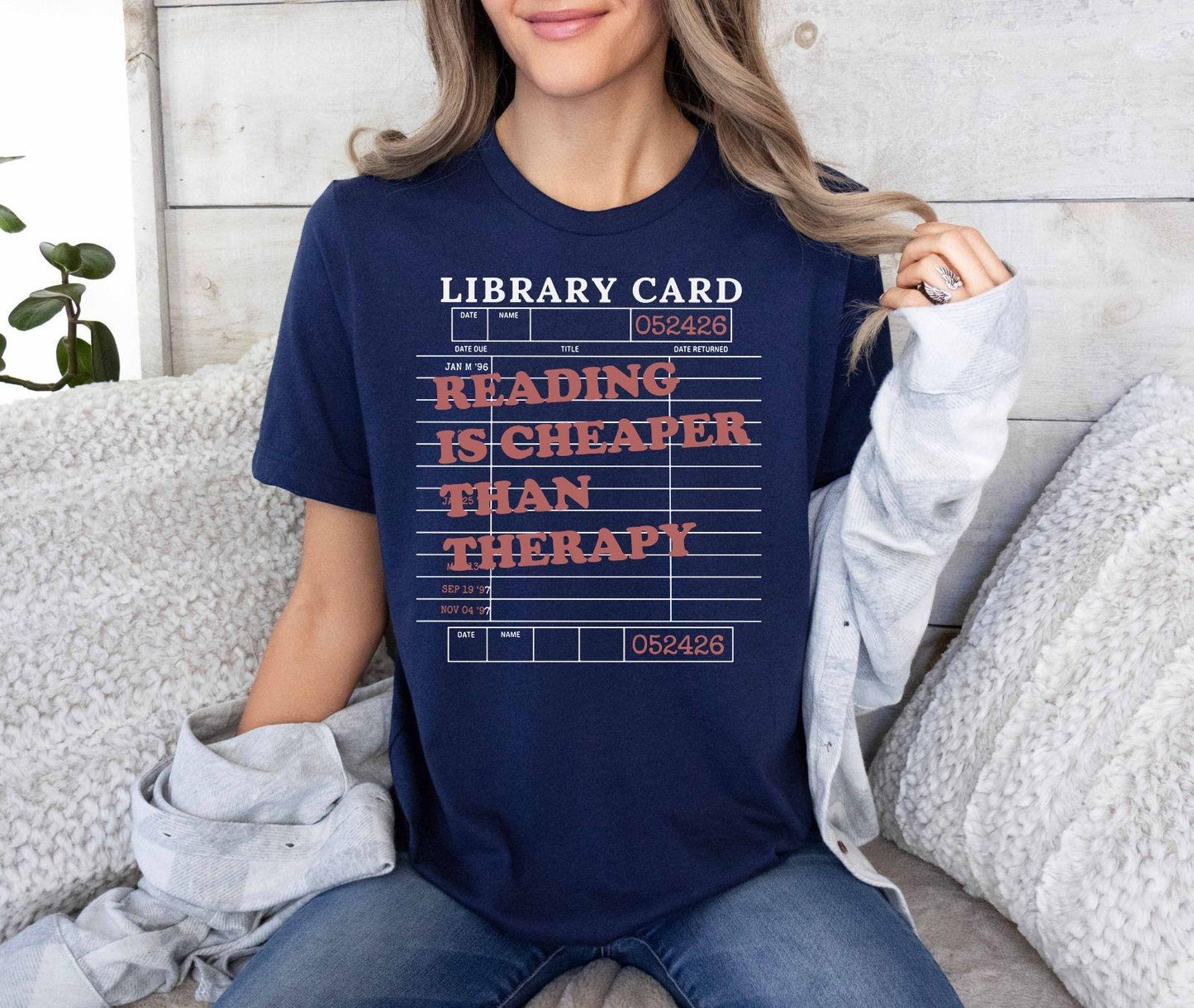 A bella canvas 3001 shirt with the saying "Reading is cheaper than therapy"