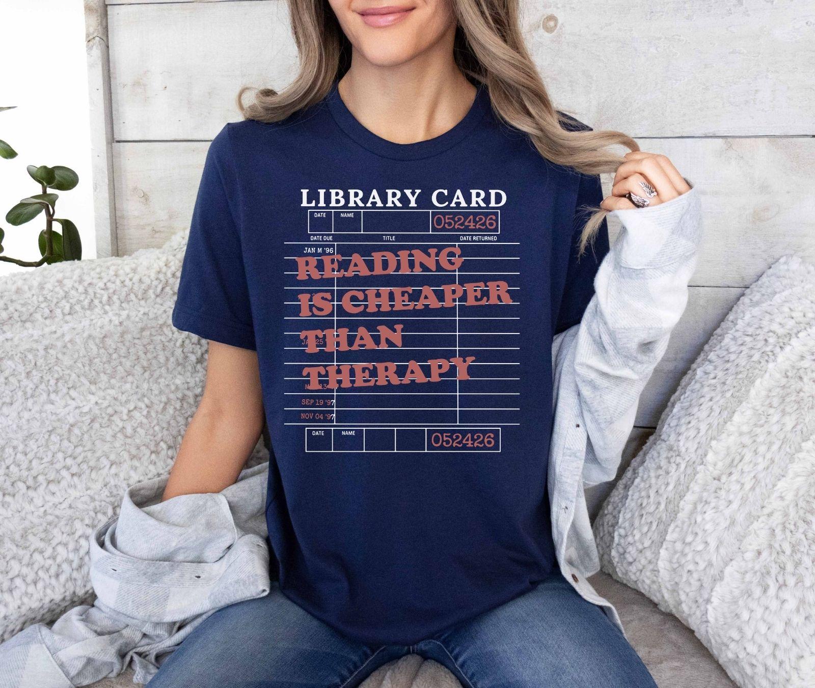 A bella canvas 3001 shirt with the saying "Reading is cheaper than therapy"