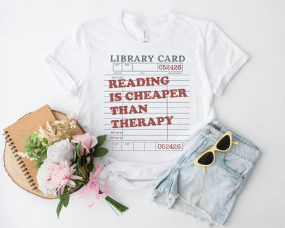 A bella canvas 3001 shirt with the saying "Reading is cheaper than therapy"