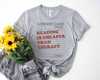 A bella canvas 3001 shirt with the saying "Reading is cheaper than therapy"
