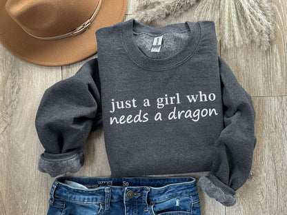 A Gildan 18000 sweatshirt with the saying "just a girl who needs a dragon"