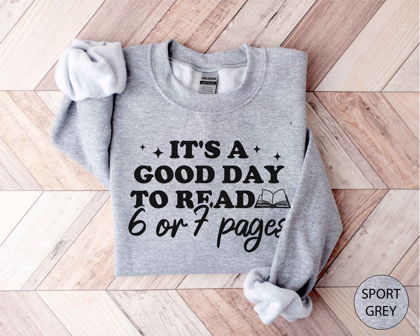 Sport grey sweatshirt with text 'It's a good day to read 6 or 7 pages' on a wooden floor.