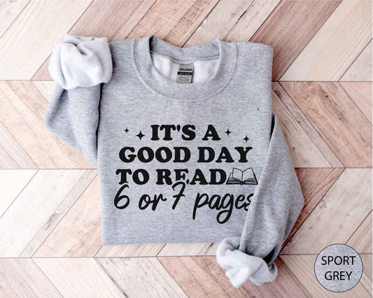 Sport grey sweatshirt with text 'It's a good day to read 6 or 7 pages' on a wooden floor.