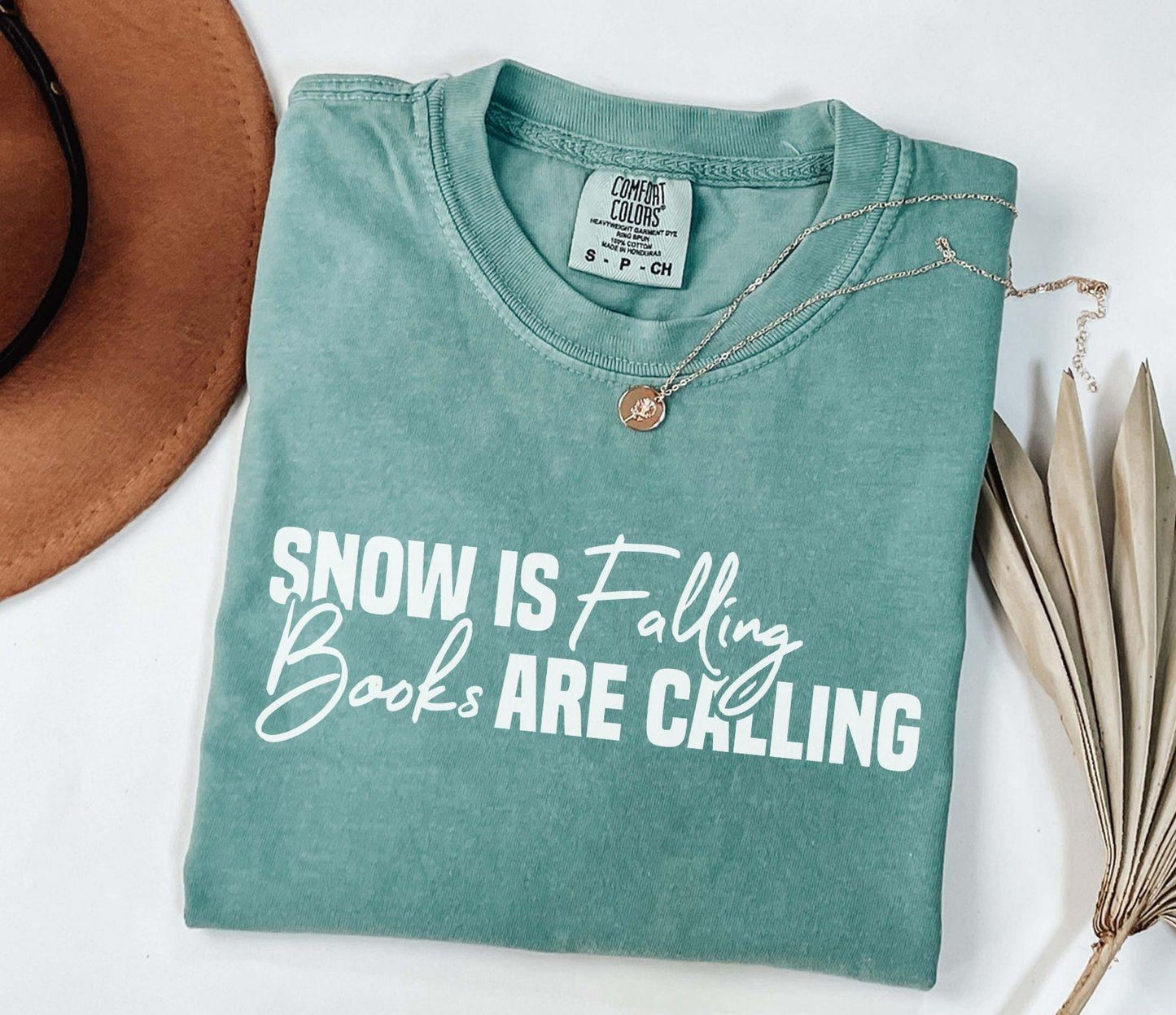 A comfort colors® shirt with the saying "Snow is falling books are calling"