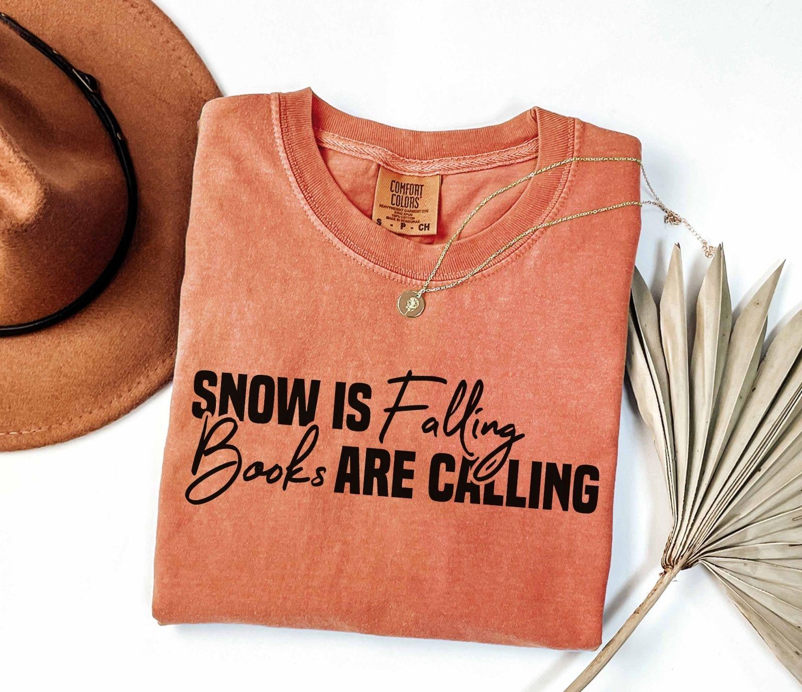 A comfort colors® shirt with the saying "Snow is falling books are calling"