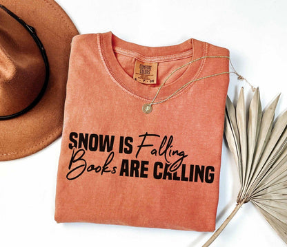 A comfort colors® shirt with the saying "Snow is falling books are calling"
