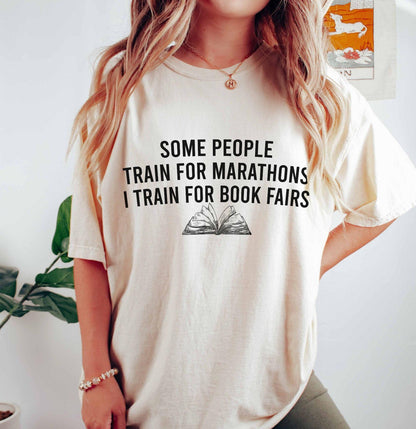 A comfort colors® shirt with the saying "some people train for marathons i train for book fairs"