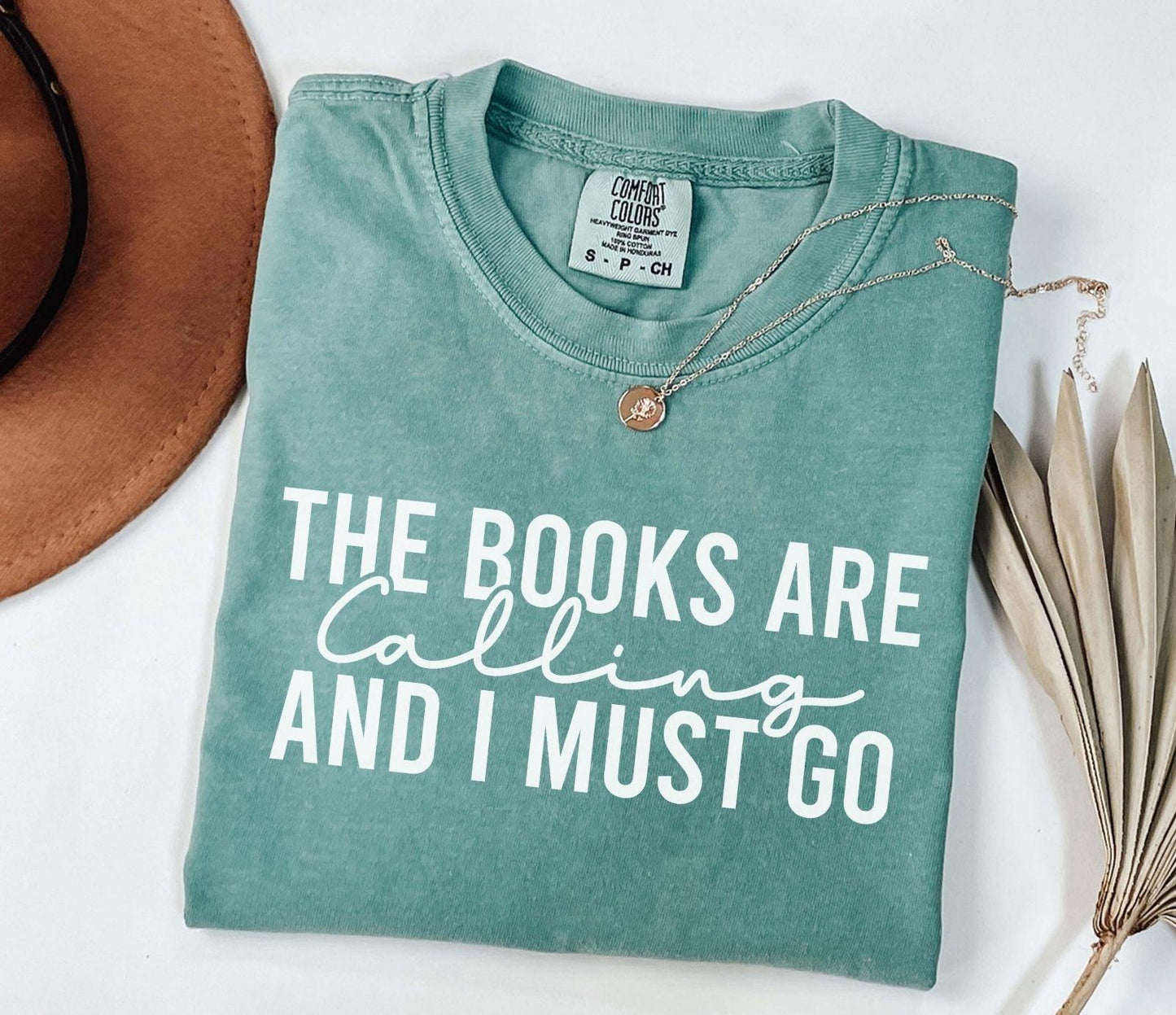 A comfort colors shirt with the saying "the books are calling and I must go"
