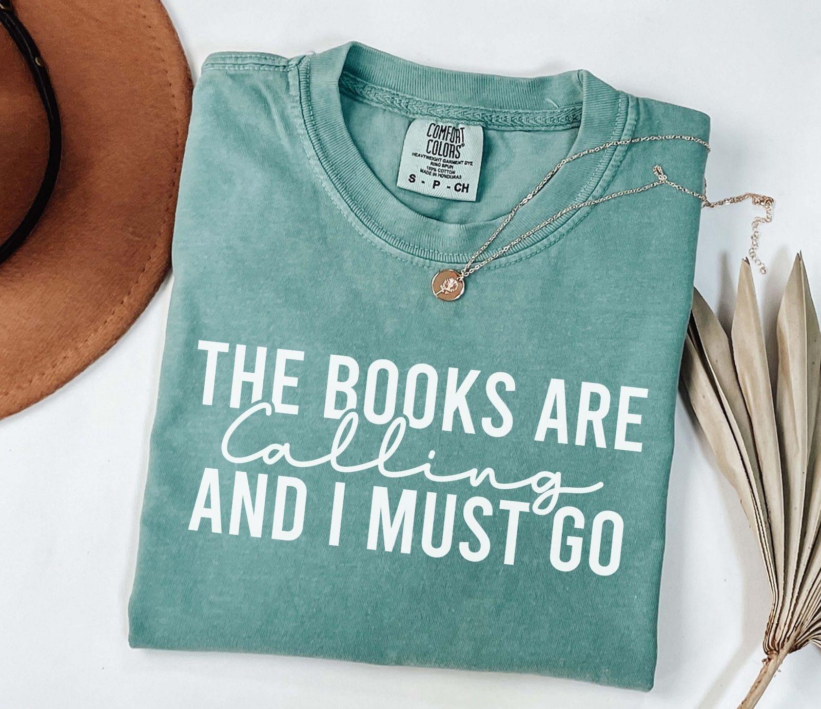 A comfort colors shirt with the saying "the books are calling and I must go"