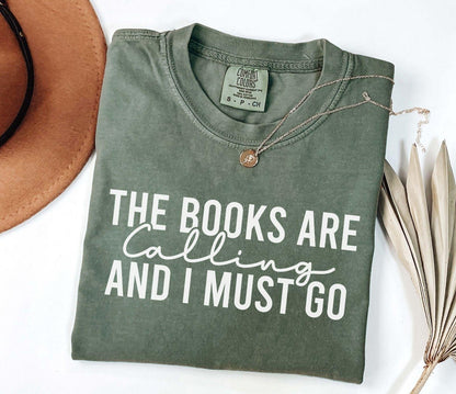 A comfort colors shirt with the saying "the books are calling and I must go"