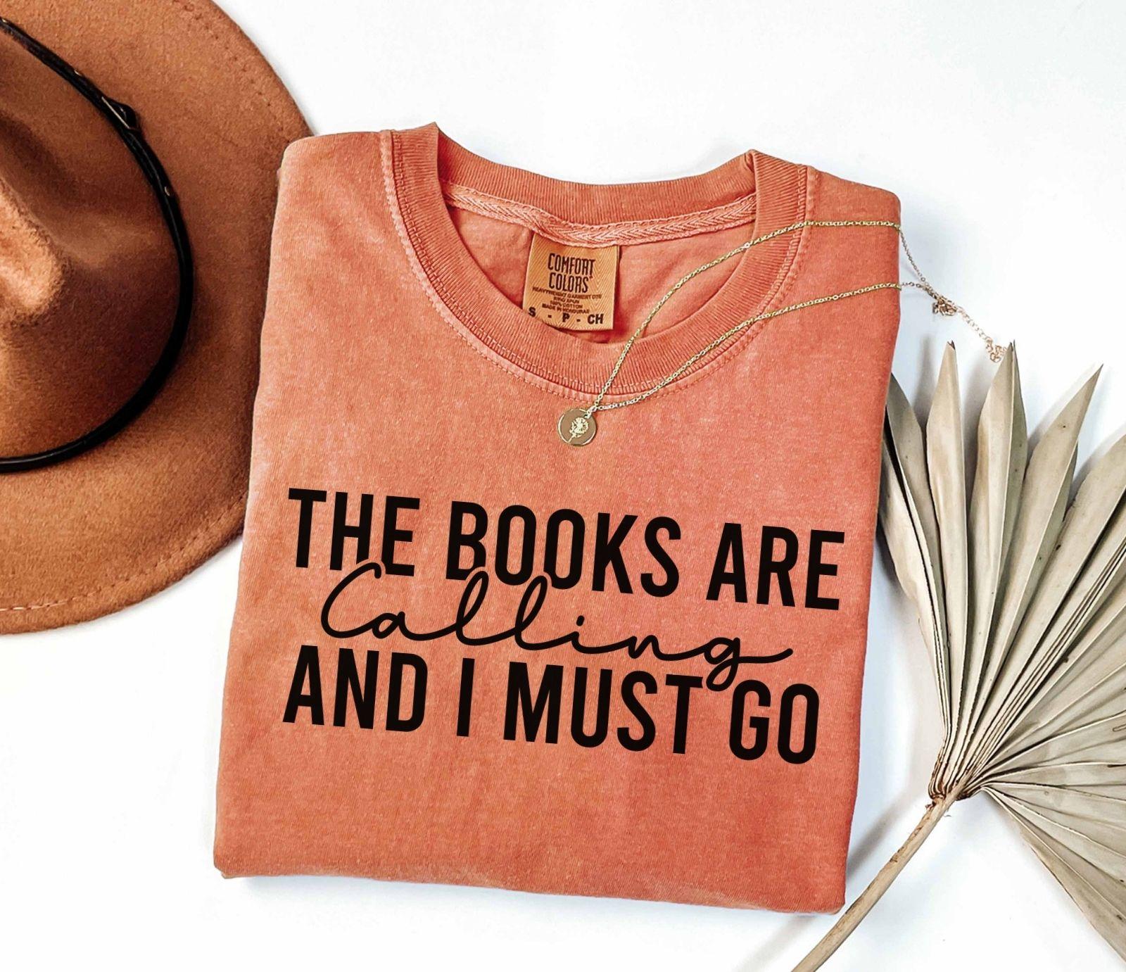 A comfort colors shirt with the saying "the books are calling and I must go"