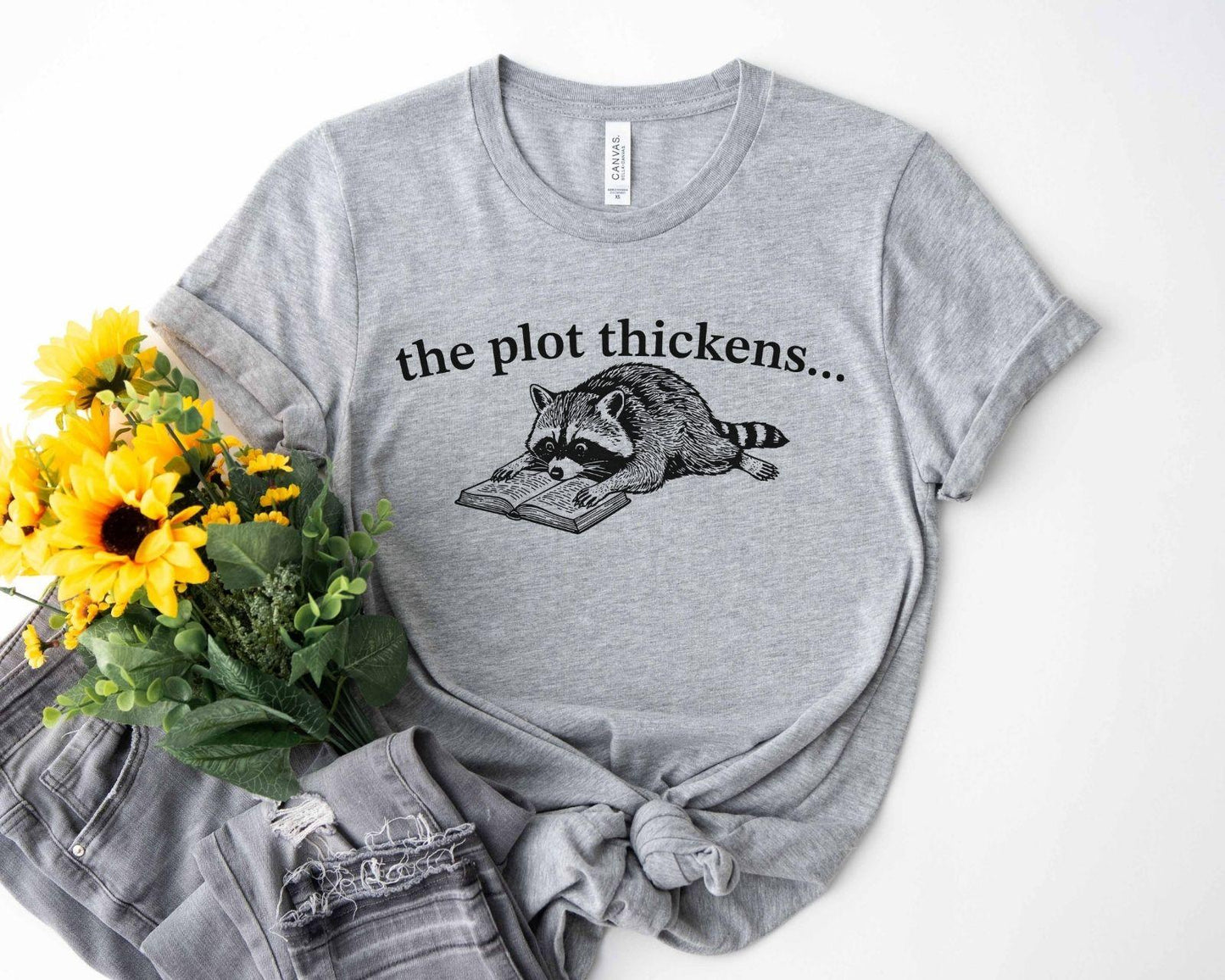 A bella canvas 3001 shirt with the saying "file:///Users/zakaria-bassim-elidrissi/Documents/Etsy/Shopify%20designs/the%20plot%20thickens"