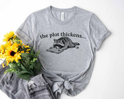 A bella canvas 3001 shirt with the saying "file:///Users/zakaria-bassim-elidrissi/Documents/Etsy/Shopify%20designs/the%20plot%20thickens"