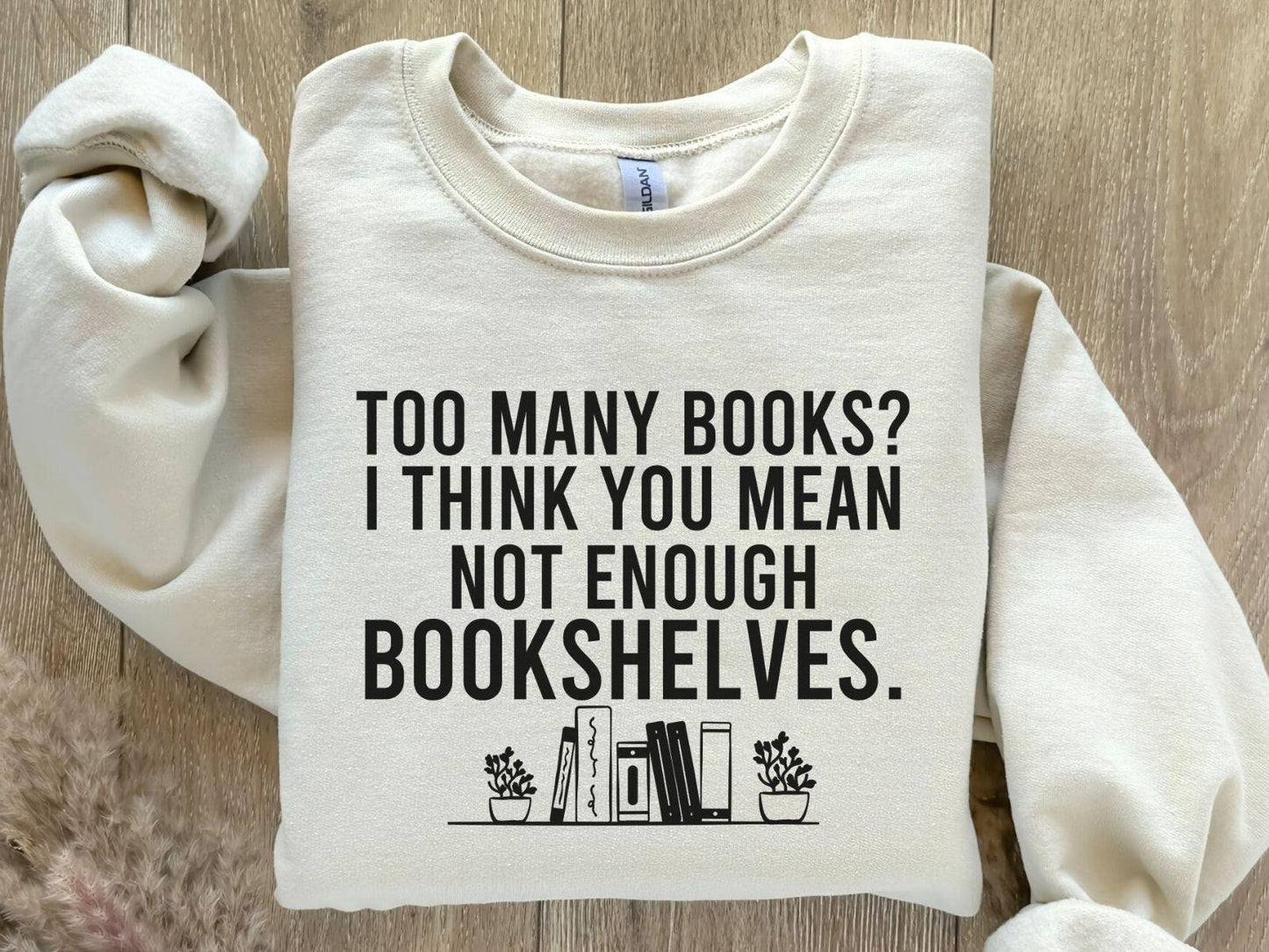 A Gildan 18000 sweatshirt with the saying "too many books I think you mean not enough bookshelves"