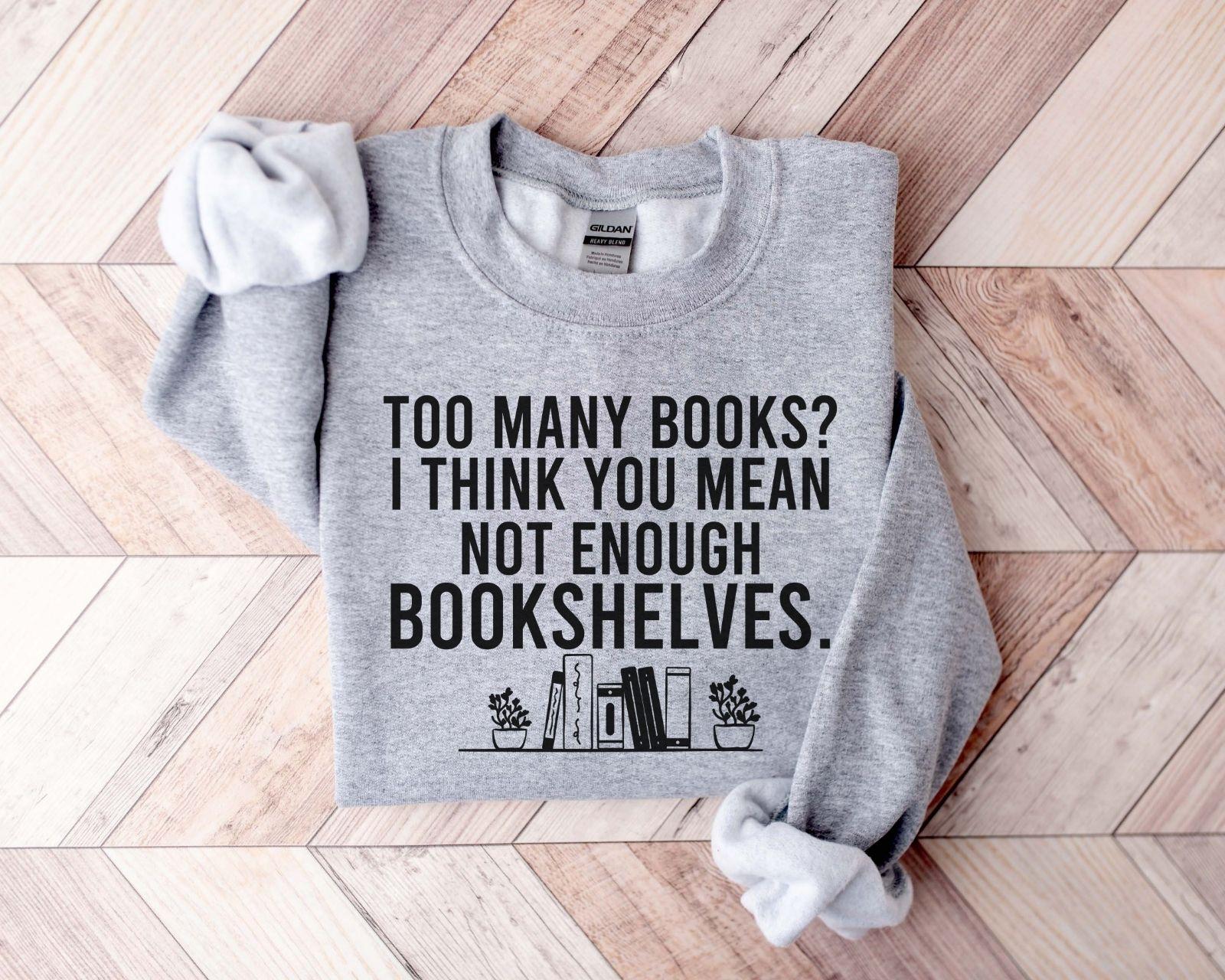A Gildan 18000 sweatshirt with the saying "too many books I think you mean not enough bookshelves"