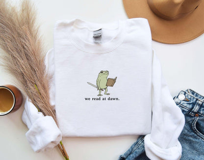A Gildan 18000 sweatshirt with the saying "we read at dawn"