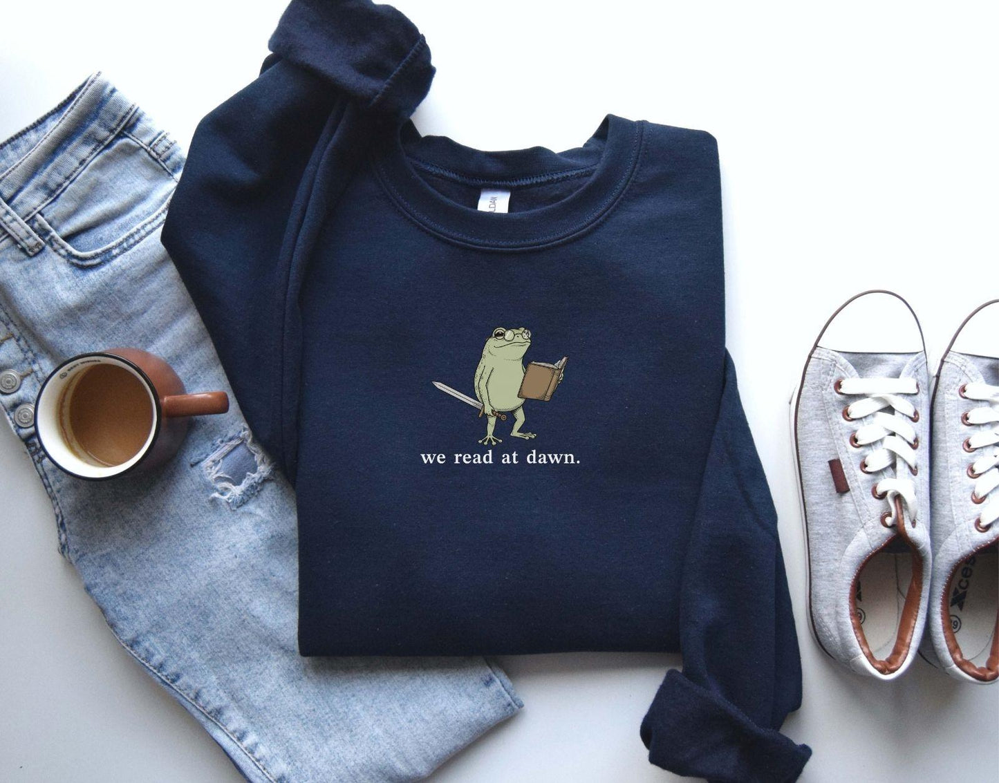 A Gildan 18000 sweatshirt with the saying "we read at dawn"