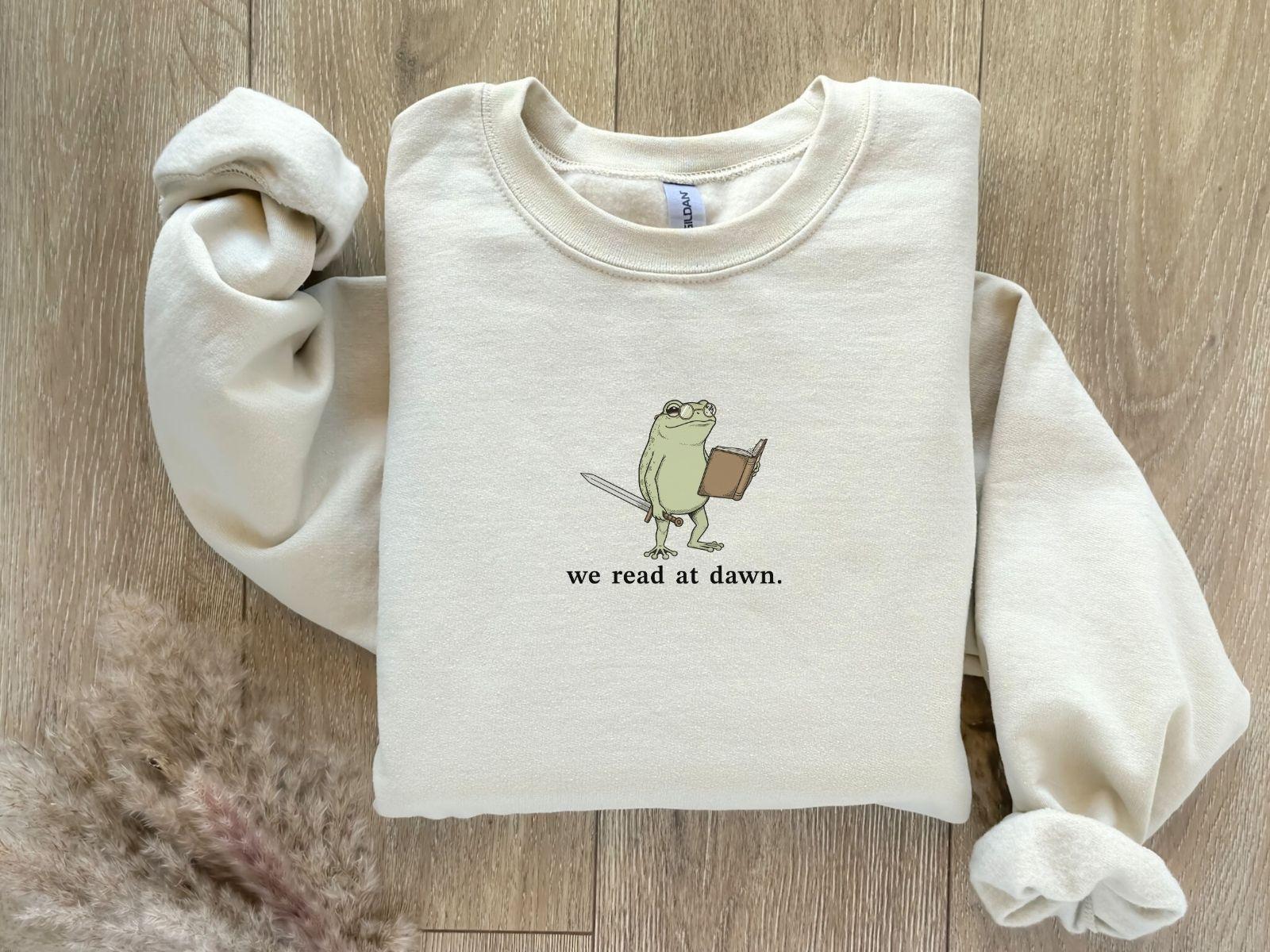 A Gildan 18000 sweatshirt with the saying "we read at dawn"
