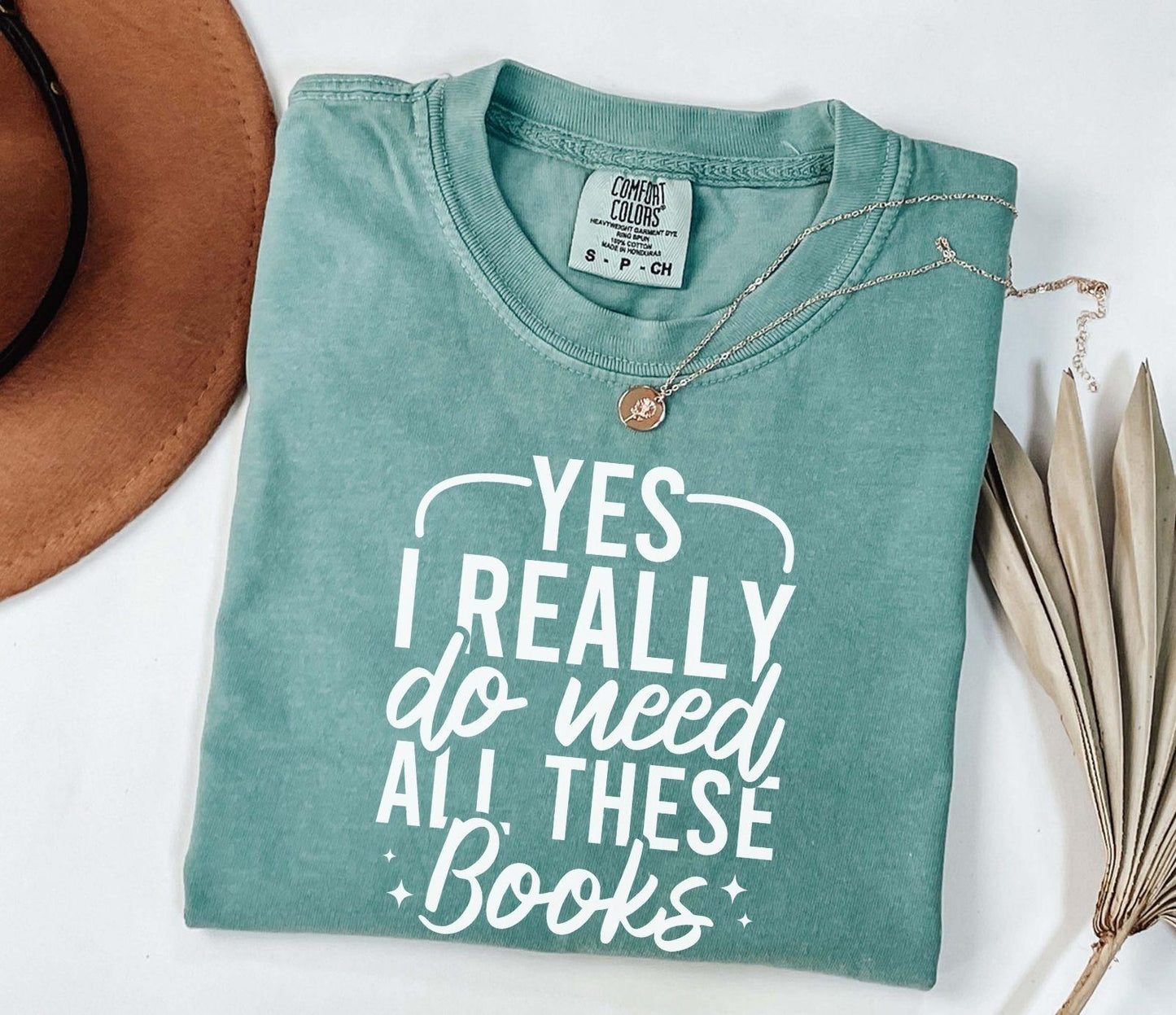 A comfort colors shirt with the saying "Yes I really do need all these books"