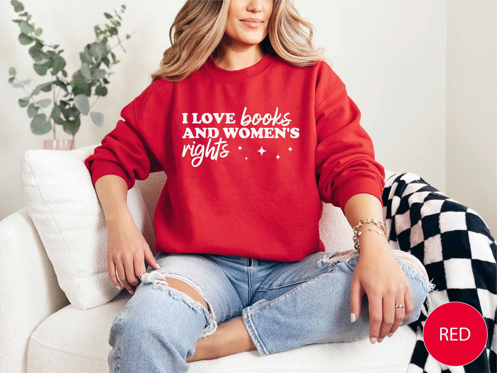 Person wearing a red sweatshirt with text, sitting on a white couch.